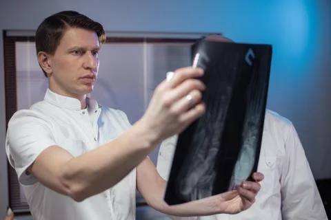 Three doctors look at an x-ray photo of a patient together Stock Photos