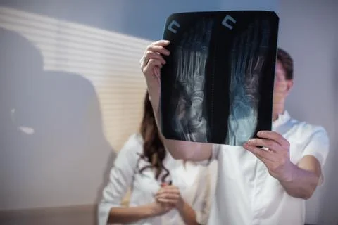 Three doctors look at an x-ray photo of a patient together Stock Photos