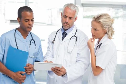 Three doctors using a tablet Stock Photos