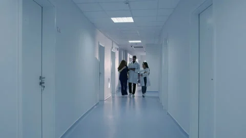 Three doctors walk down the corridor of the clinic Stock Footage 208005386