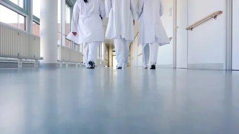Three doctors walking down a corridor in hospital Stock Footage 101602924