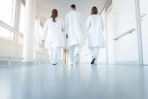 Three doctors walking down a corridor in hospital Stock Photos