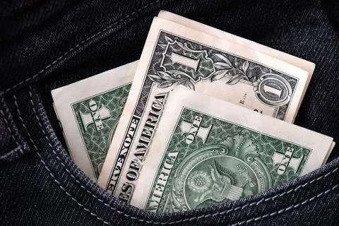 Three dollar bills stick out in the pocket of black jeans. Stockfoto's