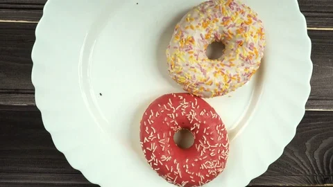 Three donuts are lying on a plate. A man's and a female hand take donuts. Stock Footage 84764887