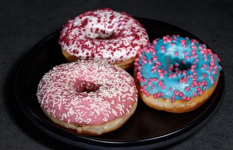 Three donuts on a black dish Stock Photos