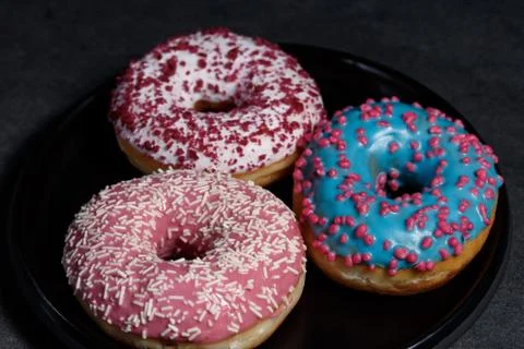 Three donuts on a black dish Stock Photos