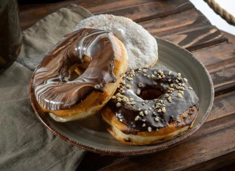 Three donuts on a design plate, backlight. Stands on a wooden tray. Stock Photos