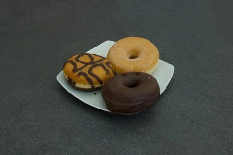 Three donuts on a white plate Stock Photos