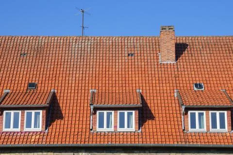 Three dormer windows with tides in a house with a tiled roof. Against the bac Stock Photos