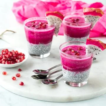 Three dragonfruit chia pudding parfaits, garnished with pomegranate arils. Stock Photos