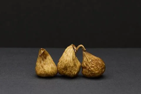 Three dried figs on dark background minimalist food still life Foto stock
