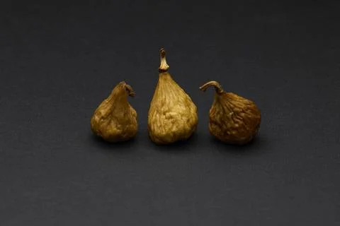 Three dried figs on dark surface natural fruit still life Foto stock