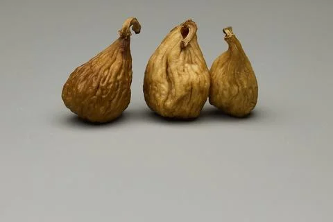 Three dried figs on gray background with soft light and minimal composition 写真素材