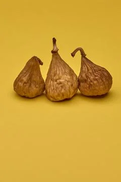 Three dried figs on yellow background colorful food still life Stock Photos
