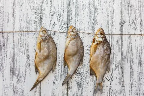 Three dried fish bream lie on a light wooden table Stock Photos