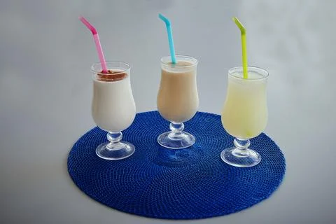 Three drinks in glasses with straws in them Stock Photos