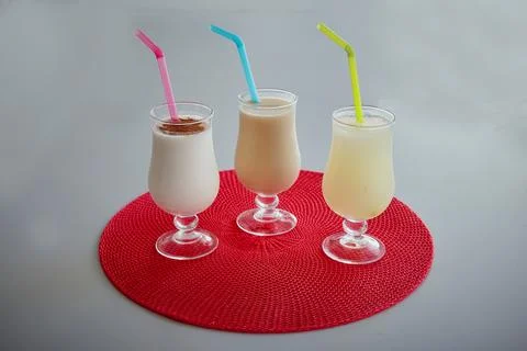 Three drinks with straws in them are on a red tablecloth Stock Photos