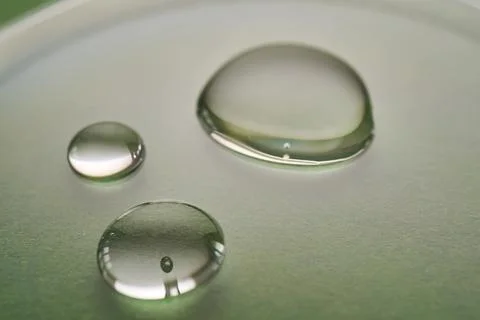 Three drops of liquid on a green background. Stock Photos