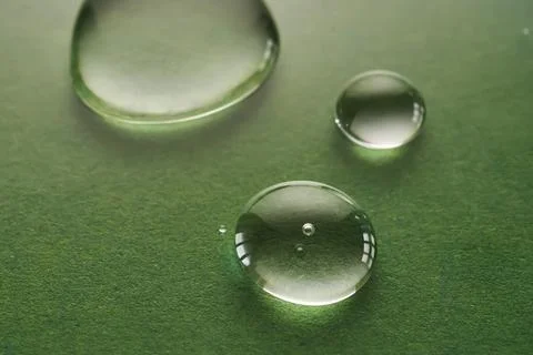 Three drops of liquid on a green background. Stock Photos