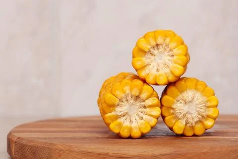 Three ears of boiled hot corn on a wooden board close-up. Stock Photos