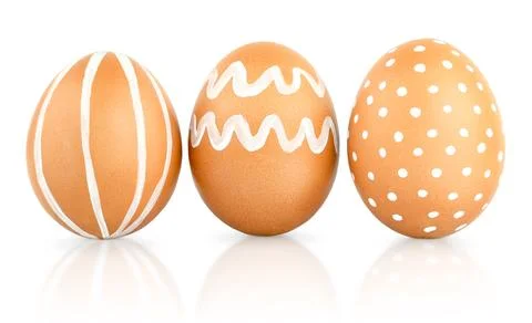 Three Easter brown eggs decorated with patterns of white paint. Natural isola Stockfoto's
