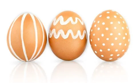 Three Easter brown eggs decorated with patterns of white paint. Natural isola Фото