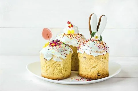 Three Easter cakes stand on a white plate on a white wooden background Stock Photos