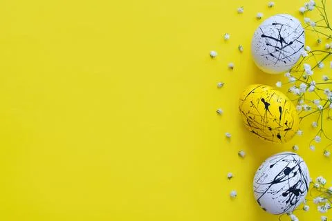 Three Easter eggs and flowers on a yellow background. Happy Easter. Minimalis Stock Photos