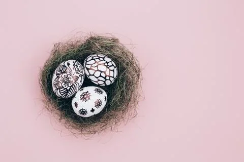 Three easter eggs are painted in black and white lie in a green nest. Stock Photos