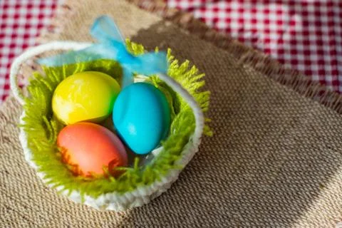 Three Easter eggs in a basket on a burlap napkin. Stock Photos