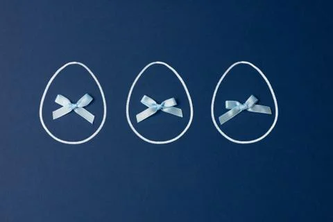 Three Easter eggs with bows on a blue background. Easter concept 写真素材
