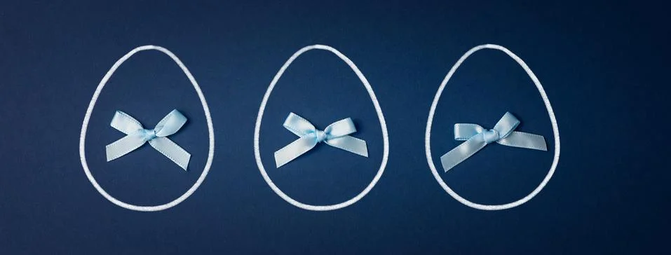 Three Easter eggs with bows on a blue background. Easter concept Stock Photos