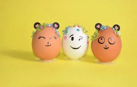 Three Easter eggs with cute faces on a yellow background. Spring. Easter. Stock Photos