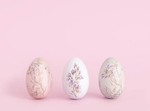Three Easter eggs decorated with a floral pattern on a pink background. 스톡 사진