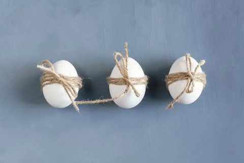 Three Easter eggs decorated with twine on a gray background. Easter card in s Stock Photos