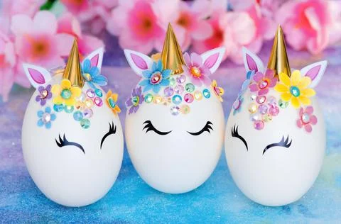 Three Easter eggs in the form of a unicorn with golden corn and flowers on Stock Photos