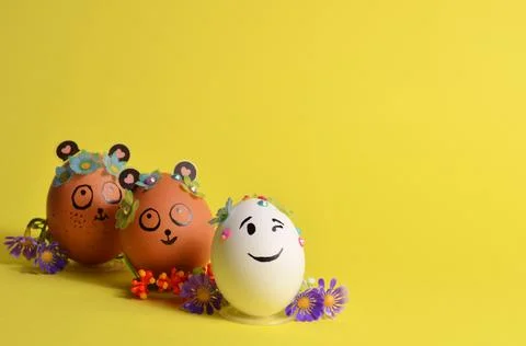 Three Easter eggs with funny faces on a yellow background. Spring. Easter. Stock Photos