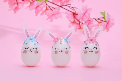 Three Easter eggs of a hare on a pink background with a flowering branch of an Stock Photos