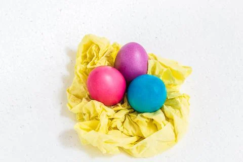 Three Easter eggs lie on yellow paper. On white background. Stock Photos