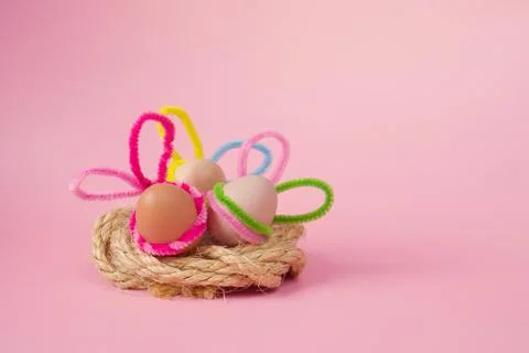 Three Easter eggs in natural color with decorated colored ears lie Stock Photos
