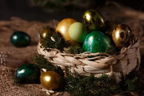 Three easter eggs in natural nest - golden, silver, bronze - with dark wooden Stock Photos