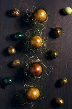 Three easter eggs in natural nest - golden, silver, bronze - with dark wooden Stock Photos