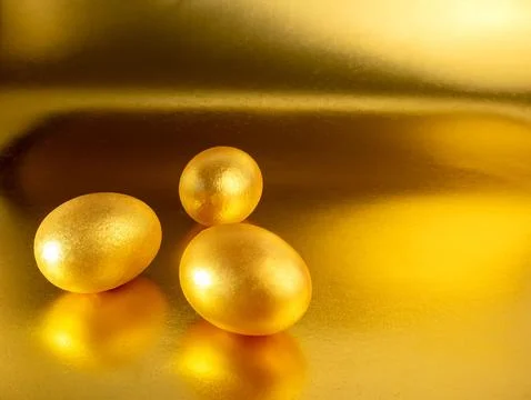 Three easter eggs painted in gold on a glittering background for the holida.. Stock Photos