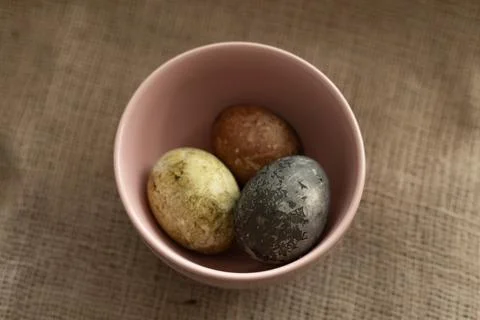 Three easter eggs in a pink bowl on a burlap texture background Foto stock