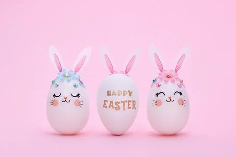 Three Easter eggs in a row on a pink background with copy space. Stock Photos