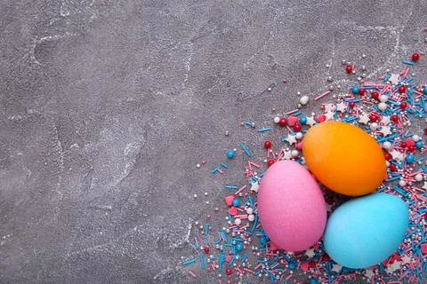 Three easter eggs with sprinkles on a grey cement background Stock Photos