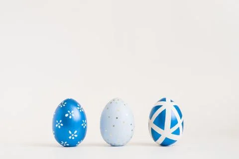 Three Easter golden decorated eggs on blue background. Minimal easter concept Stock Photos