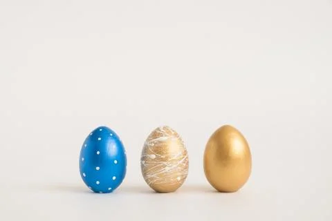 Three Easter golden decorated eggs on blue background. Minimal easter concept Stockfoto's
