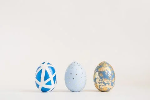 Three Easter golden decorated eggs on blue background. Minimal easter concept Stockfoto's