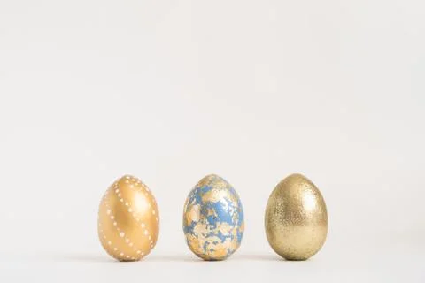 Three Easter golden decorated eggs on blue background. Minimal easter concept 스톡 사진